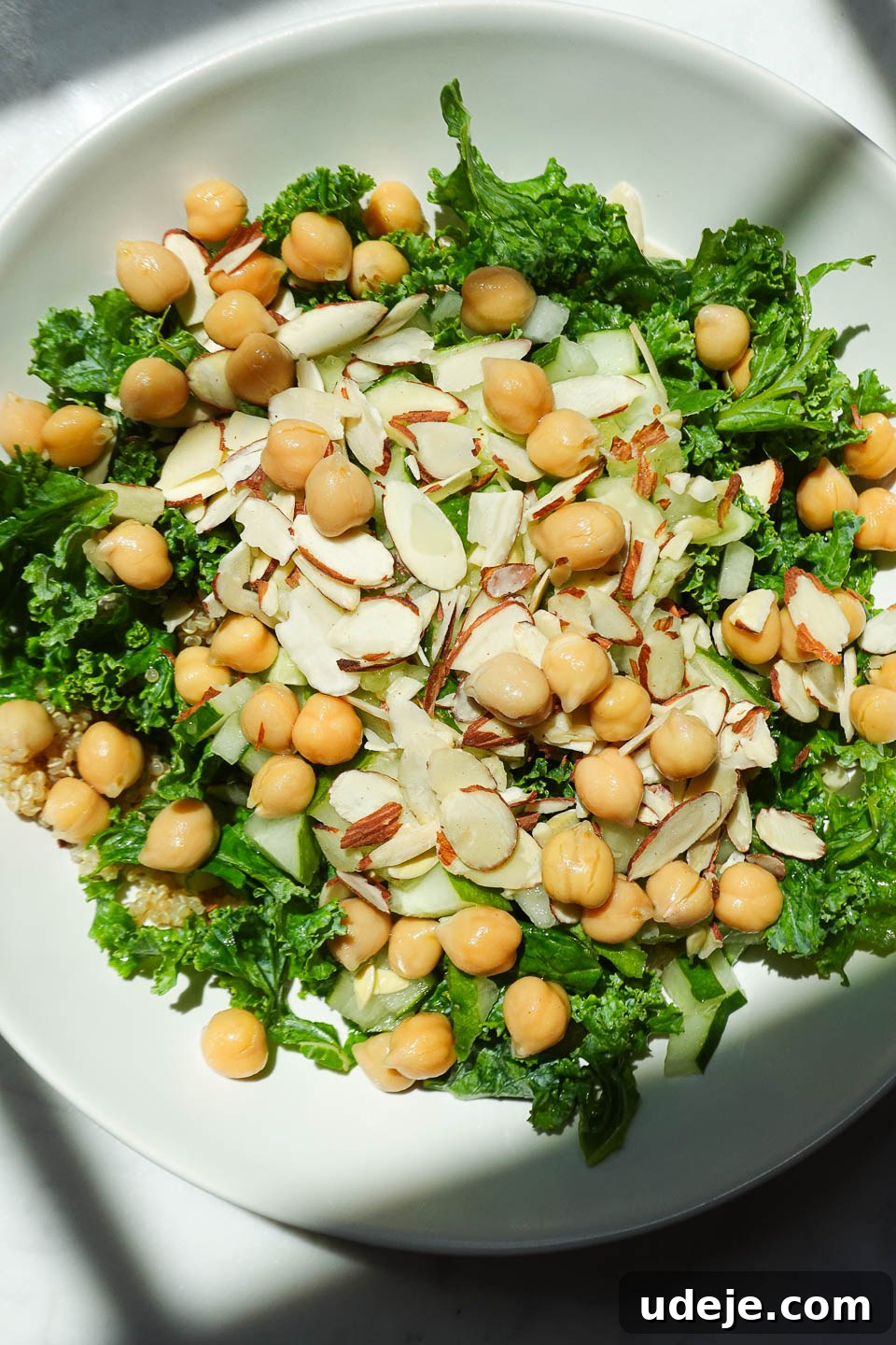 Quick Plant-Based Chickpea Quinoa Bowl 5 Close-up of vibrant quinoa salad showcasing kale, chickpeas, cucumber, and glistening sliced almonds