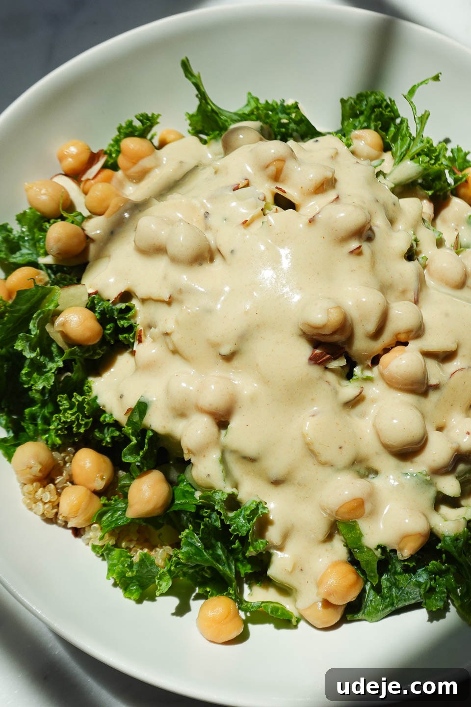 Quick Plant-Based Chickpea Quinoa Bowl 6 Artistic shot of lemon tahini dressing being generously poured over a colorful chickpea quinoa salad