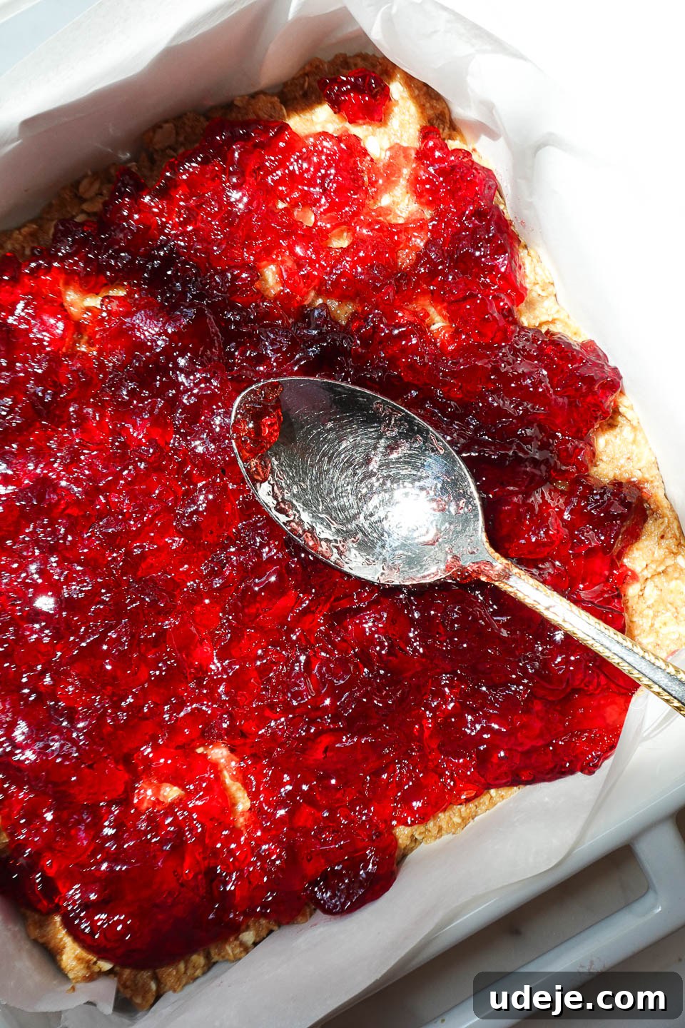Spreading grape jelly over peanut butter oat crust for homemade PB&J bars