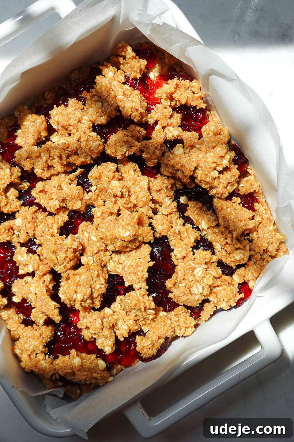 Crumbling oat topping over grape jelly layer before baking PB&J bars