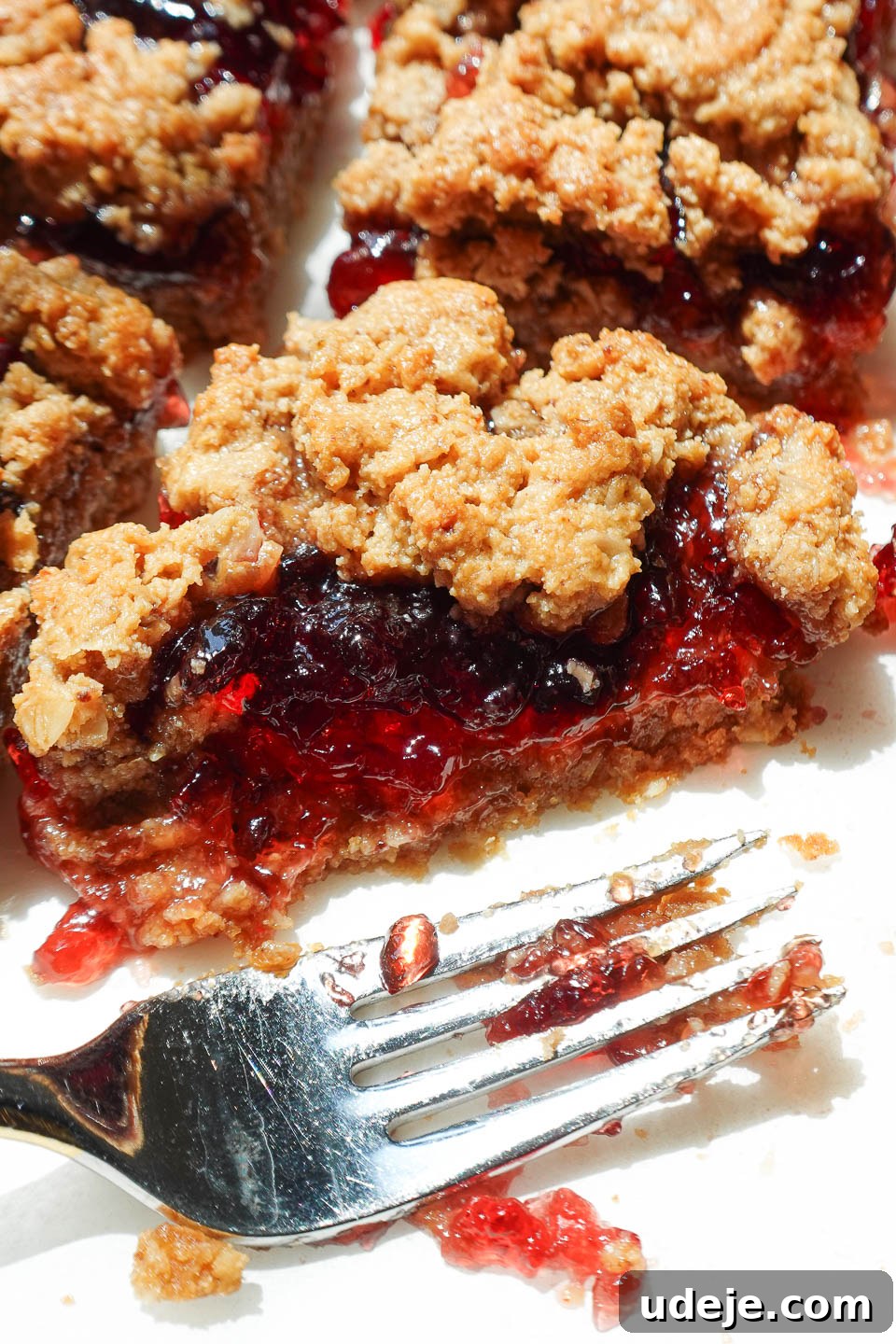 Close-up of a soft, chewy PB&J bar with golden oat crust and jammy center