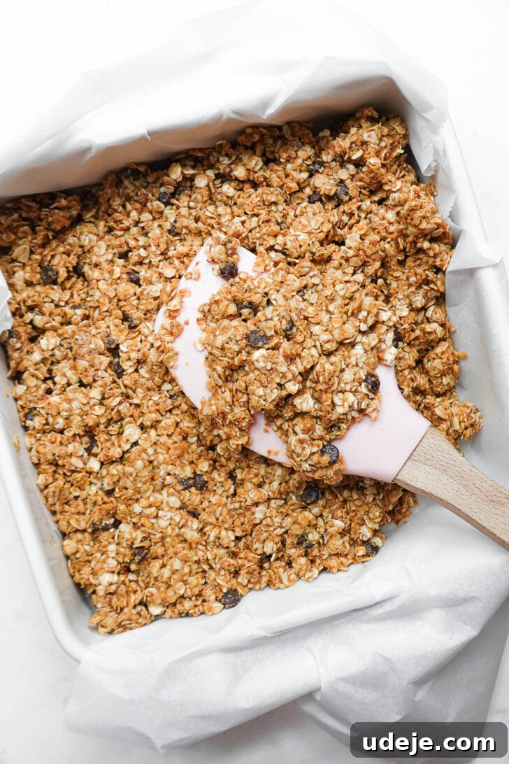 Nourishing Plant-Based Gluten-Free Granola Bars 5 Granola bar mixture evenly pressed into a parchment-lined 8x8 inch baking pan, ready for chilling