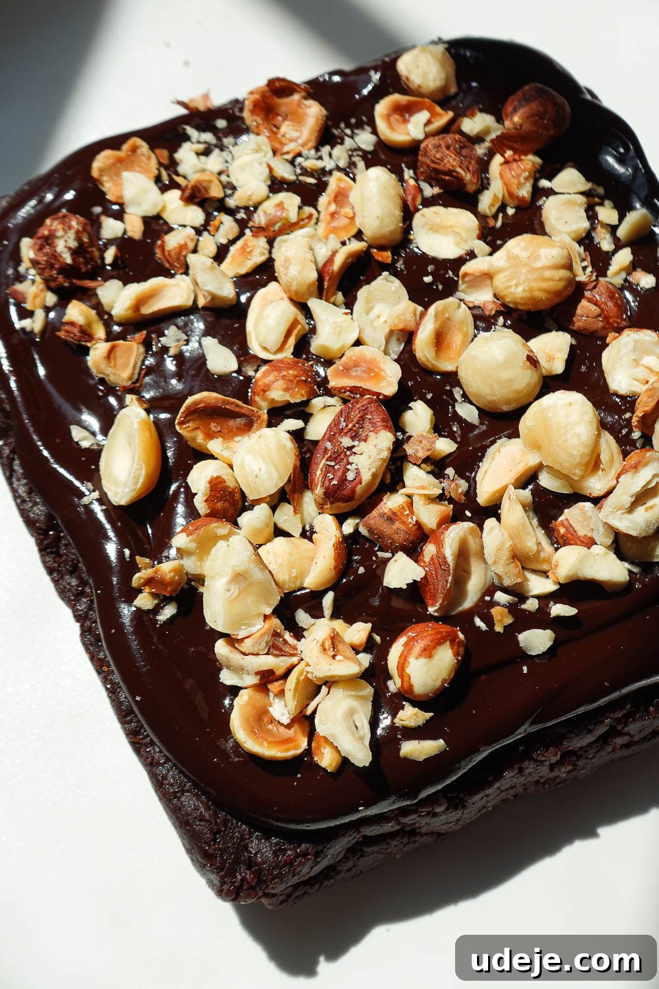 Healthy vegan and gluten-free brownies made with dates and almond butter and topped with a 2 ingredient chocolate ganache and chopped hazelnuts