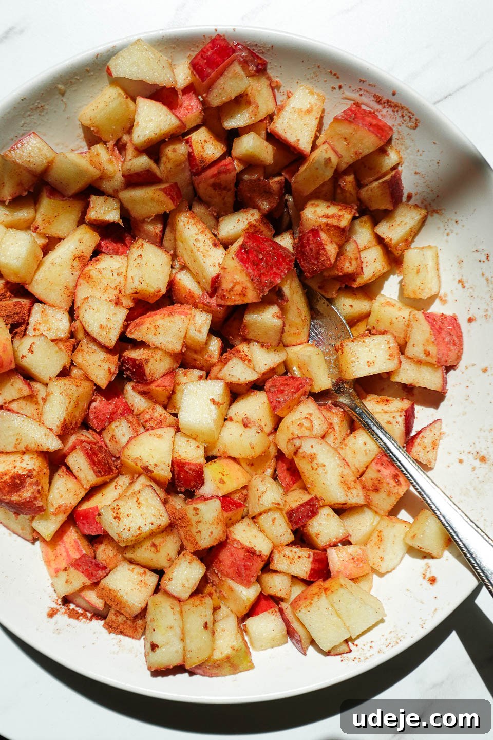 Air Fried Cinnamon Apples 7 Freshly diced apples in a bowl tossed with maple syrup and cinnamon