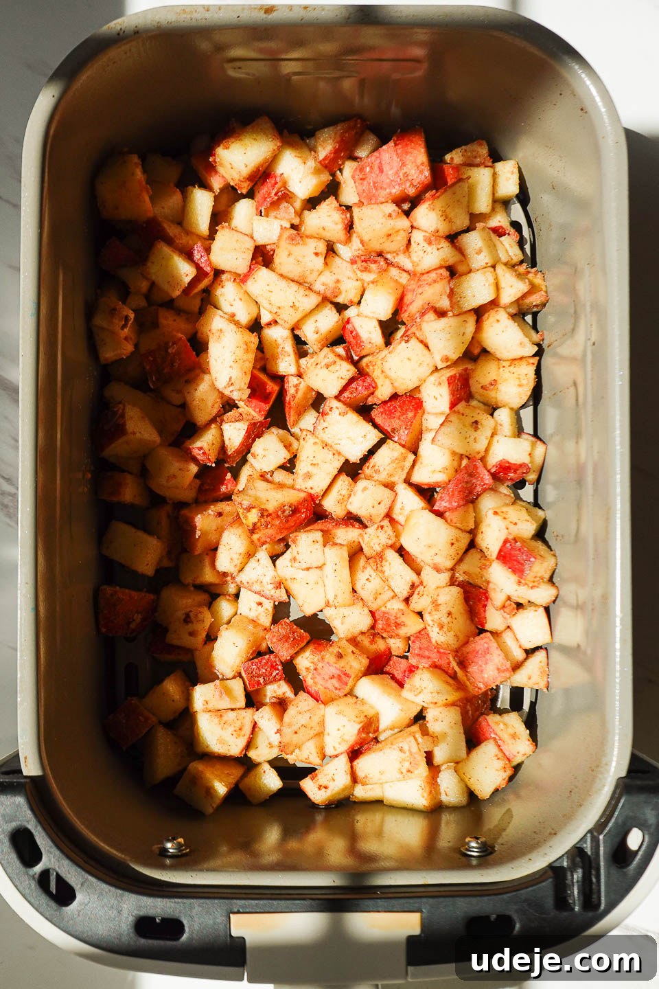 Air Fried Cinnamon Apples 8 Close-up of diced apples evenly spread in the air fryer basket