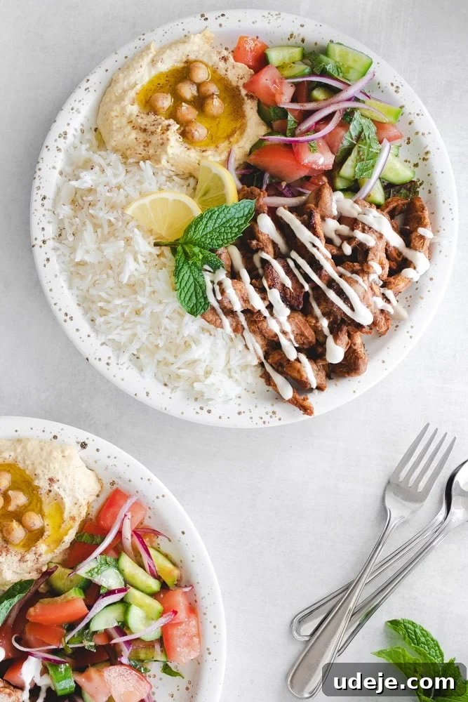Authentic Chicken Shawarma Platter 3 Close-up of a Chicken Shawarma plate showcasing the layers of hummus, rice, seasoned chicken, and a fresh salad, ready to be enjoyed.