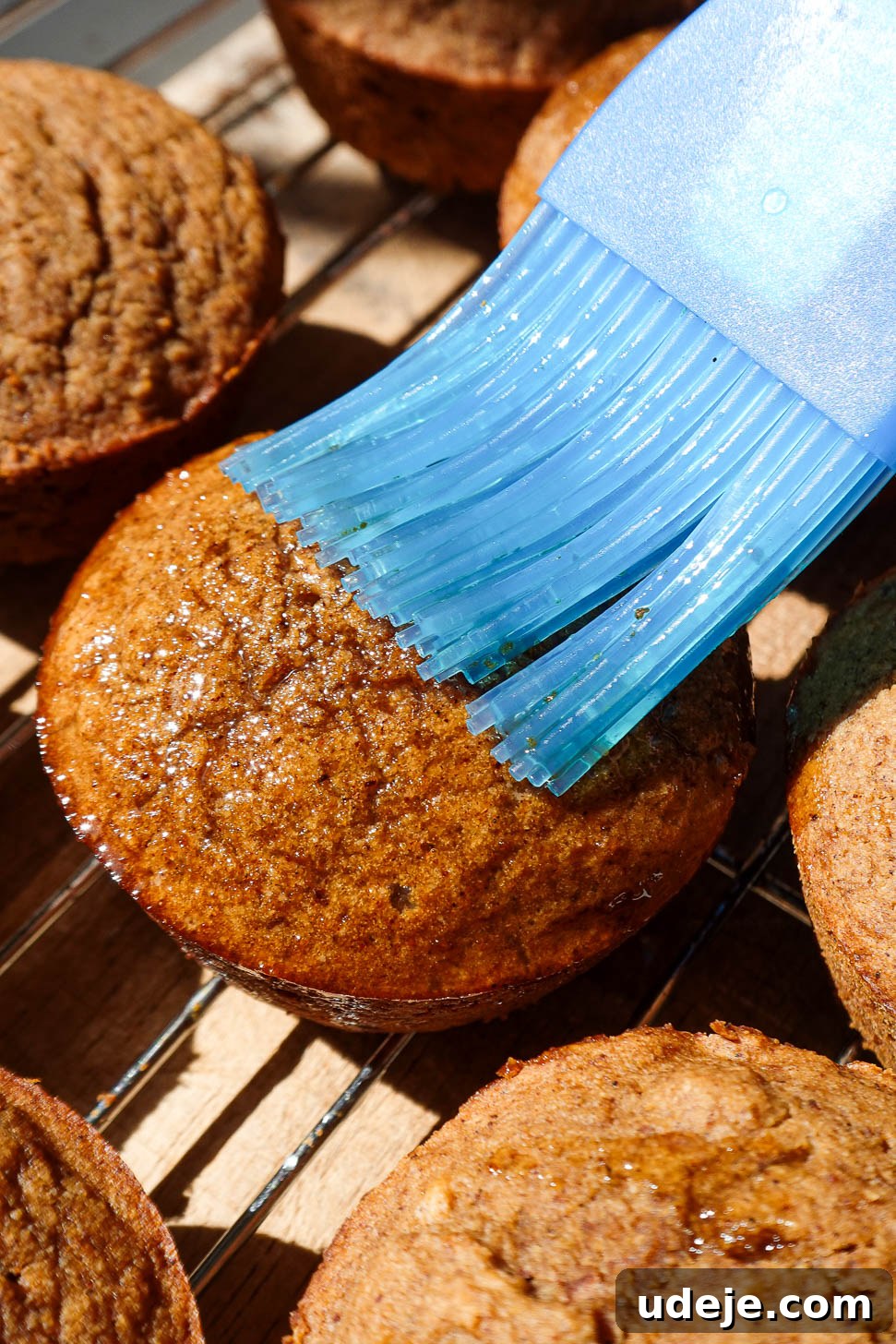 Autumn Spiced Apple Cider Muffins 7 Freshly baked apple cider muffins being brushed with melted coconut oil