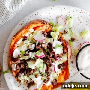 Stuffed sweet potatoes served with fresh vegetables and a creamy yogurt tahini sauce, showcasing a wholesome and appealing meal.