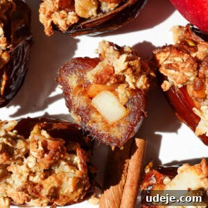 Bite taken out of an apple crisp stuffed date showing gooey date and cinnamon apple center