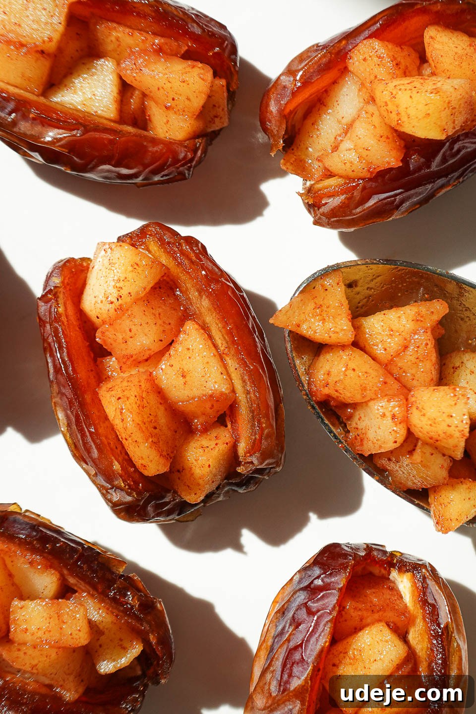 Golden Apple Crisp Date Bites 4 Medjool dates sliced open and stuffed with cinnamon apples on a baking sheet, ready for the crisp topping.