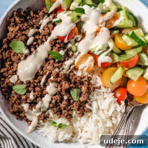 A beautifully presented Middle Eastern Ground Beef Bowl, showcasing perfectly cooked, seasoned ground beef, fluffy white rice, a crisp chopped salad, and a luscious tahini sauce, all ready to be savored.