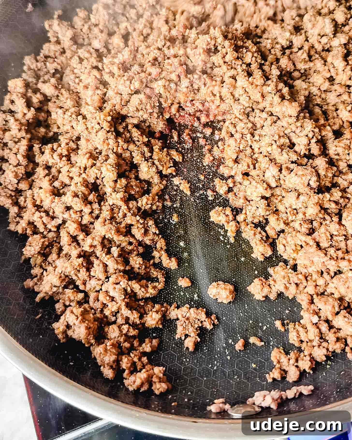 Easy Middle Eastern Spiced Beef Bowls 4 Partially cooked brown ground beef in a dark colored skillet, showing the browning process.