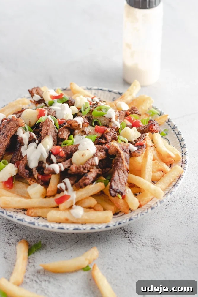 Shawarma Beef Poutine Twist 4 Beef shawarma poutine served in a plate with someone about to dig in using a fork