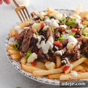 Beef shawarma poutine served in a plate with someone about to dig in using a fork