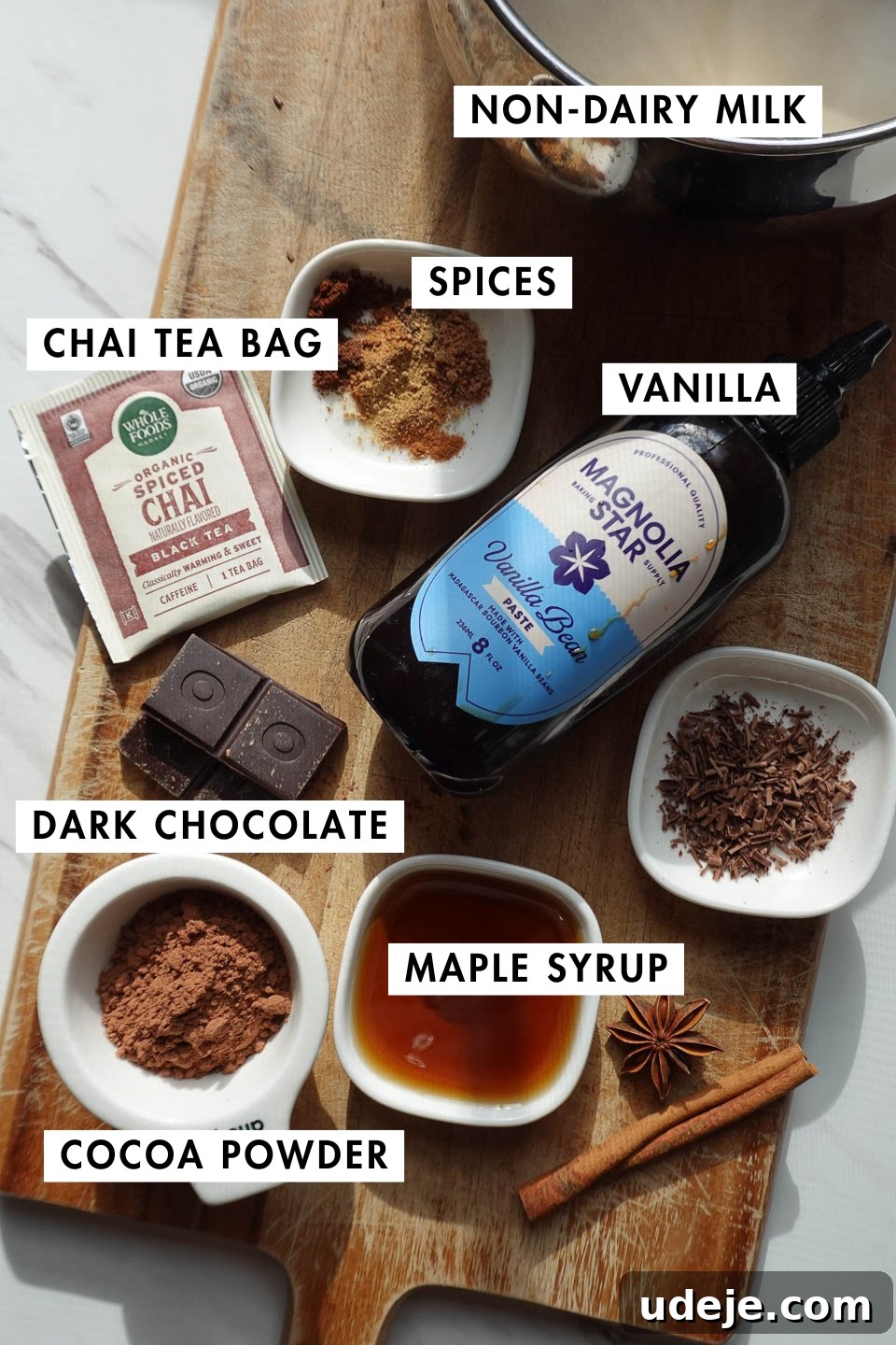 Velvet Vanilla Chai Hot Chocolate 3 Arrangement of ingredients for vanilla chai hot chocolate: chai tea bag, non-dairy milk, dark chocolate, cocoa powder, maple syrup, vanilla bean paste, and a selection of ground spices.