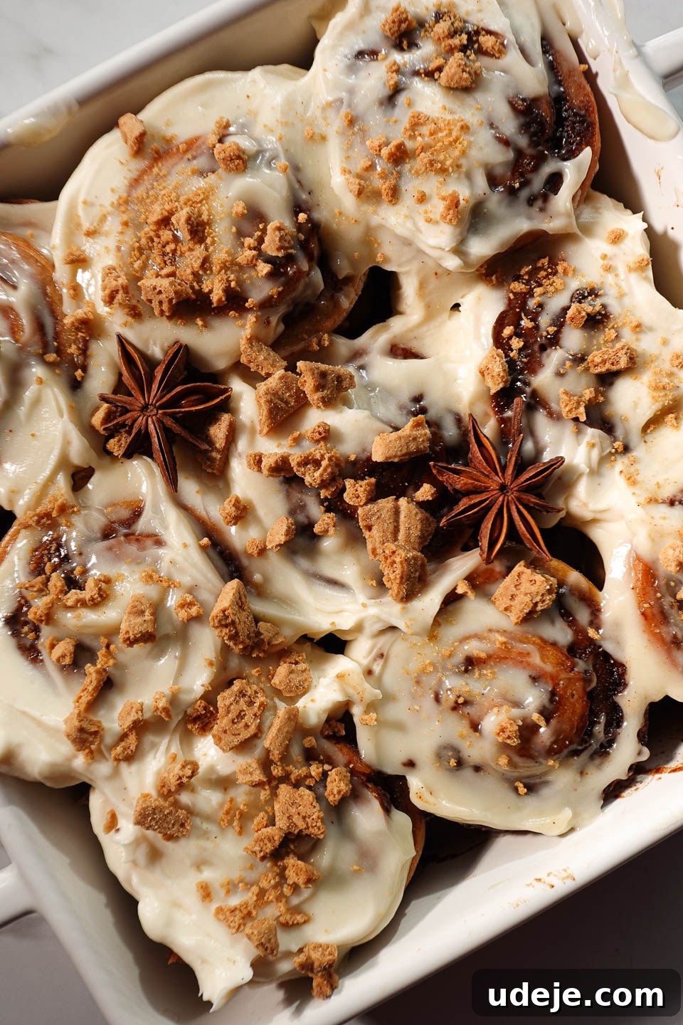 Cozy Vegan Gluten-Free Gingerbread Swirls 9 Close-up of gingerbread cinnamon rolls showing tight, defined swirls and creamy cream cheese frosting topped with crushed graham crackers and star anise pods