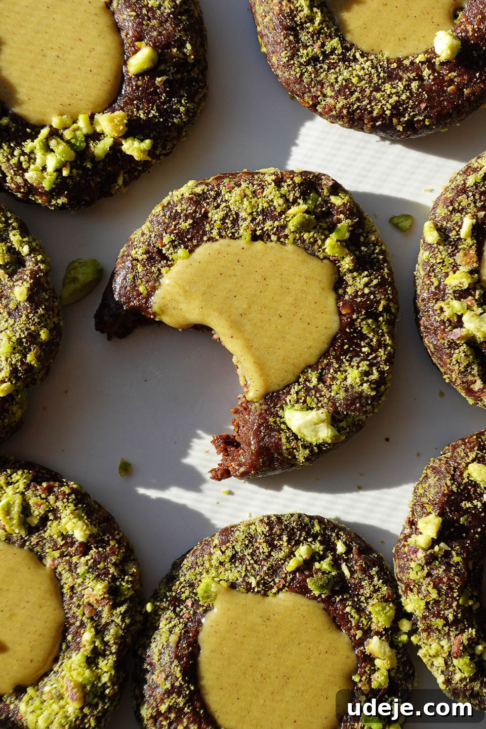 Effortless Vegan Gluten Free Pistachio Thumbprint Treats 2 overhead shot of no-bake pistachio thumbprint cookies rolled in crushed pistachios and filled with pistachio butter