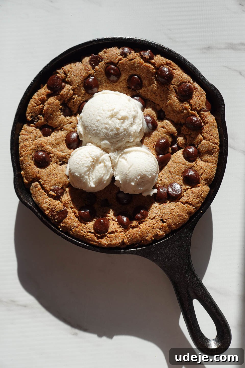 Gooey Skillet Chocolate Chip Cookie Perfection (Vegan and Gluten-Free) 11 Adding scoops of creamy vanilla ice cream to a warm chocolate chip skillet cookie, creating a perfect à la mode dessert.