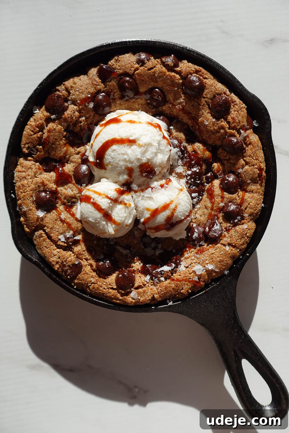 Gooey Skillet Chocolate Chip Cookie Perfection (Vegan and Gluten-Free) 12 Drizzling date syrup and flaky sea salt over a chocolate chip cookie skillet à la mode, highlighting the final touches.