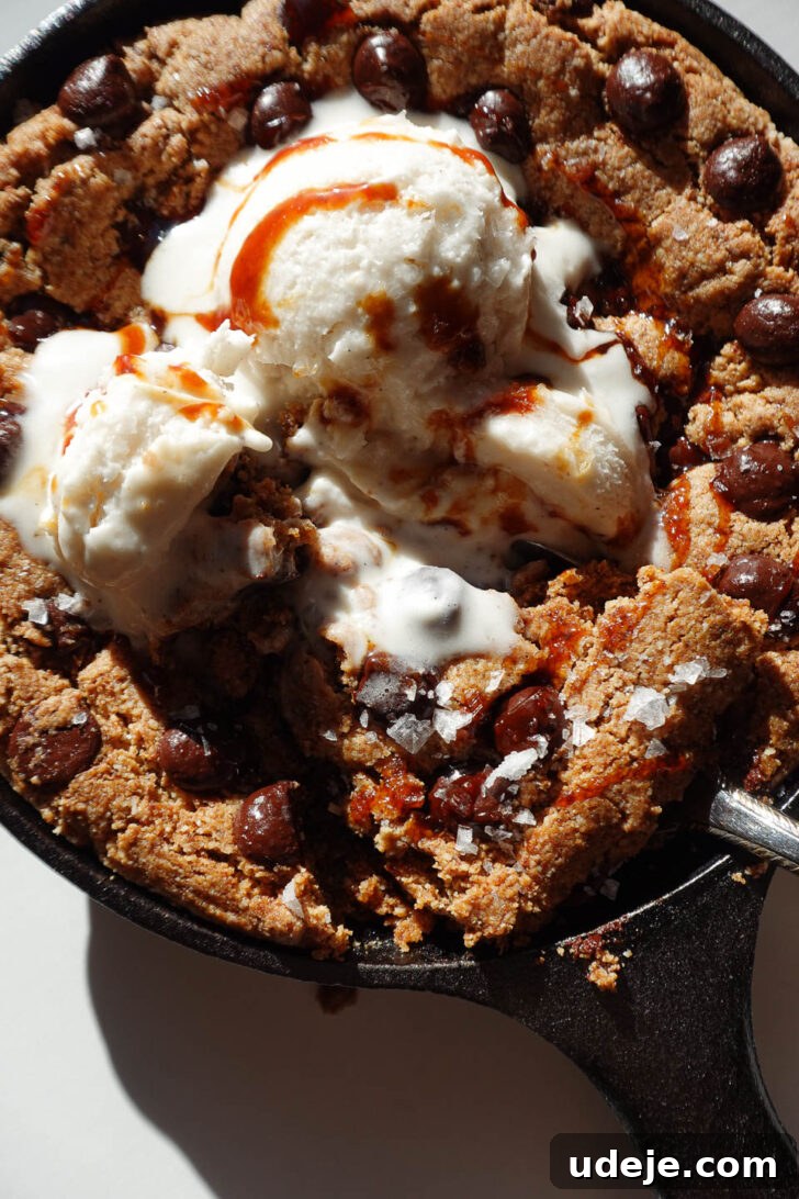 Gooey Skillet Chocolate Chip Cookie Perfection (Vegan and Gluten-Free) 5 Digging a spoon into a soft and gooey chocolate chip cookie skillet warm from the oven, showing its irresistible texture.