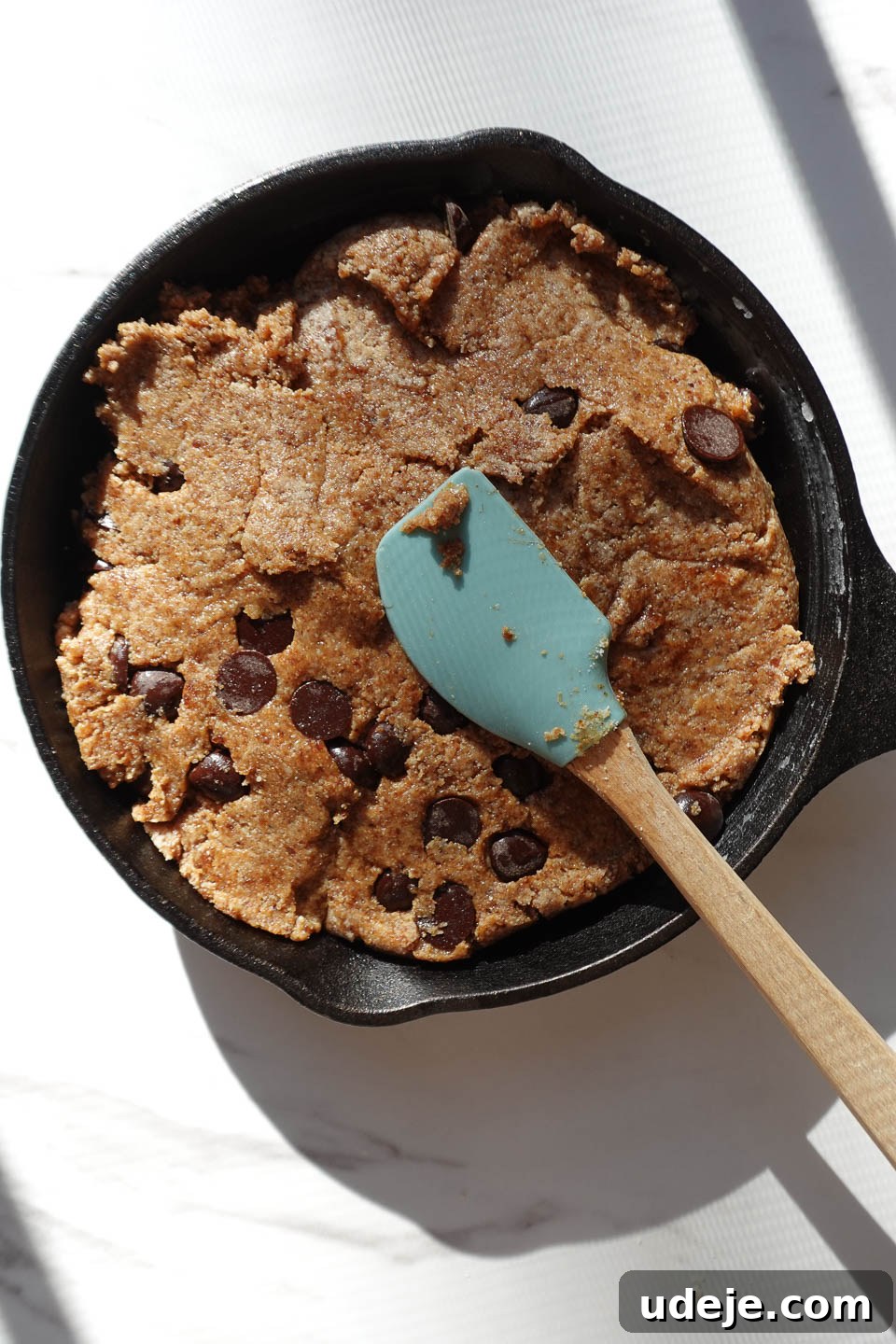 Gooey Skillet Chocolate Chip Cookie Perfection (Vegan and Gluten-Free) 8 Pressing chocolate chip cookie dough evenly into a cast iron skillet, demonstrating the preparation step.