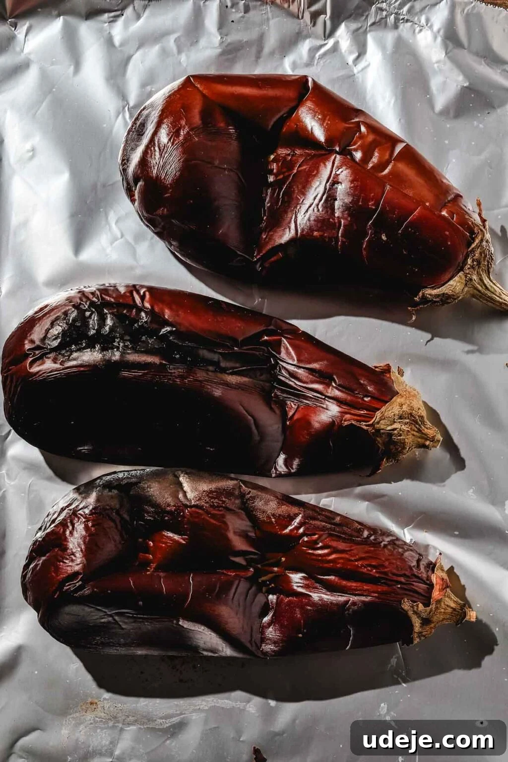 Charred Eggplant Baba Ghanoush 5 Three large eggplants on a foil-lined baking sheet, fully roasted until softened and charred, indicating they are ready for the next step of preparation.