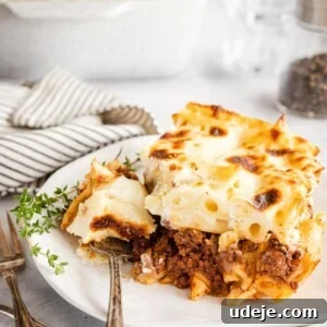 Creamy Bechamel Macaroni Bake 10 A slice of Bechamel Pasta bake on a plate with a piece cut out using a fork
