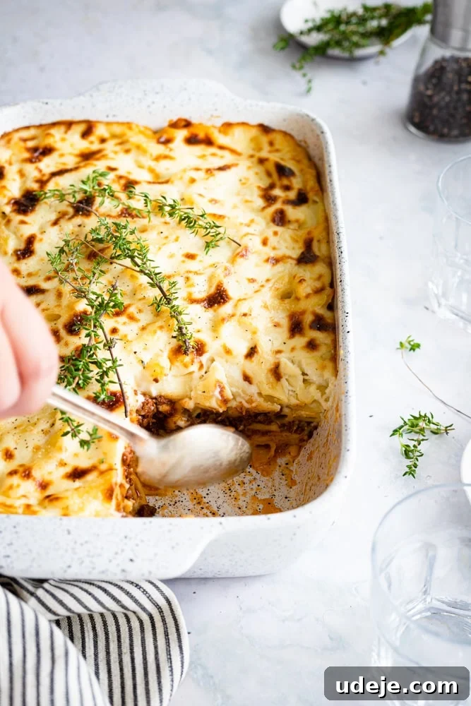 Creamy Bechamel Macaroni Bake 9 A large casserole dish of Bechamel Pasta bake with one generous piece removed, revealing the creamy layers beneath.