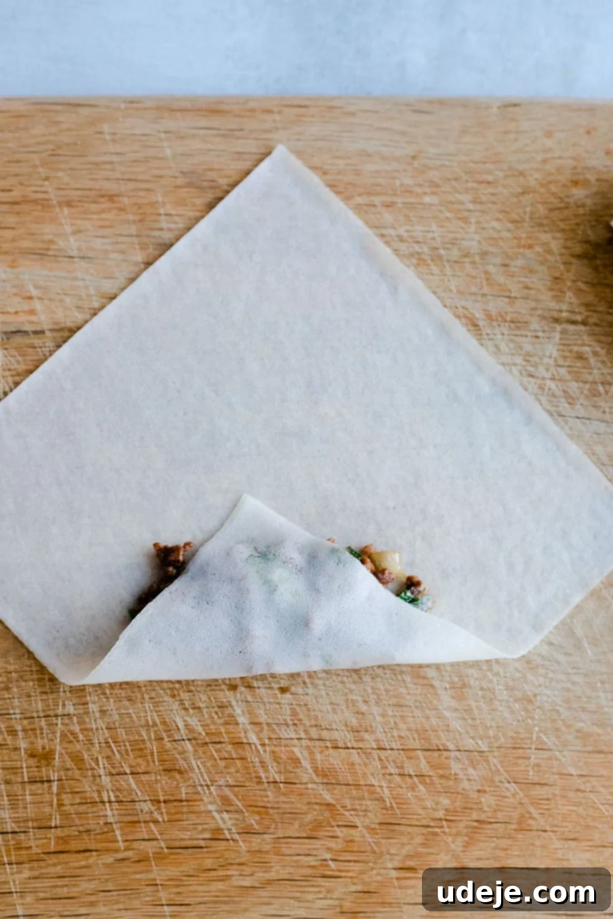 Your Guide to Authentic Homemade Sambousek 13 a square spring roll wrapper on a wooden board, with ground beef filling inside
