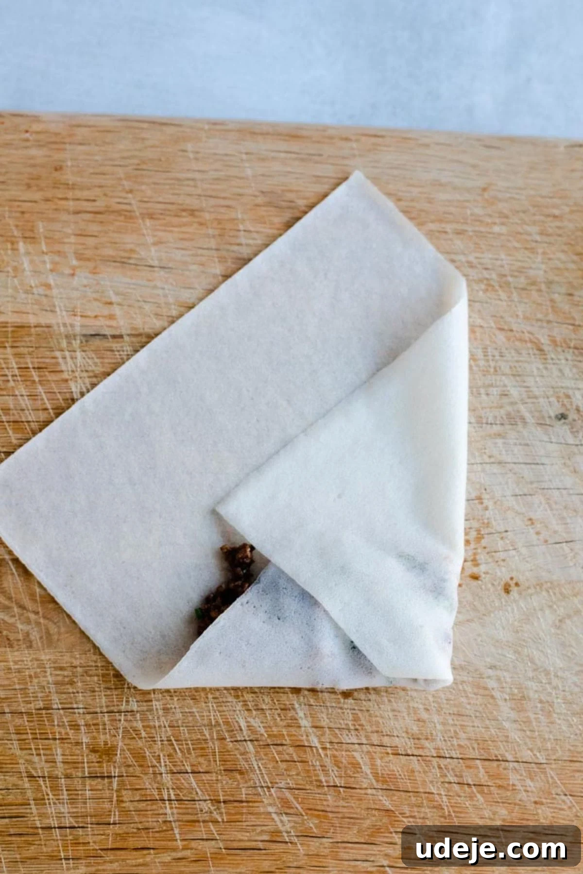 Your Guide to Authentic Homemade Sambousek 14 a square spring roll wrapper on a wooden board, with ground beef filling inside