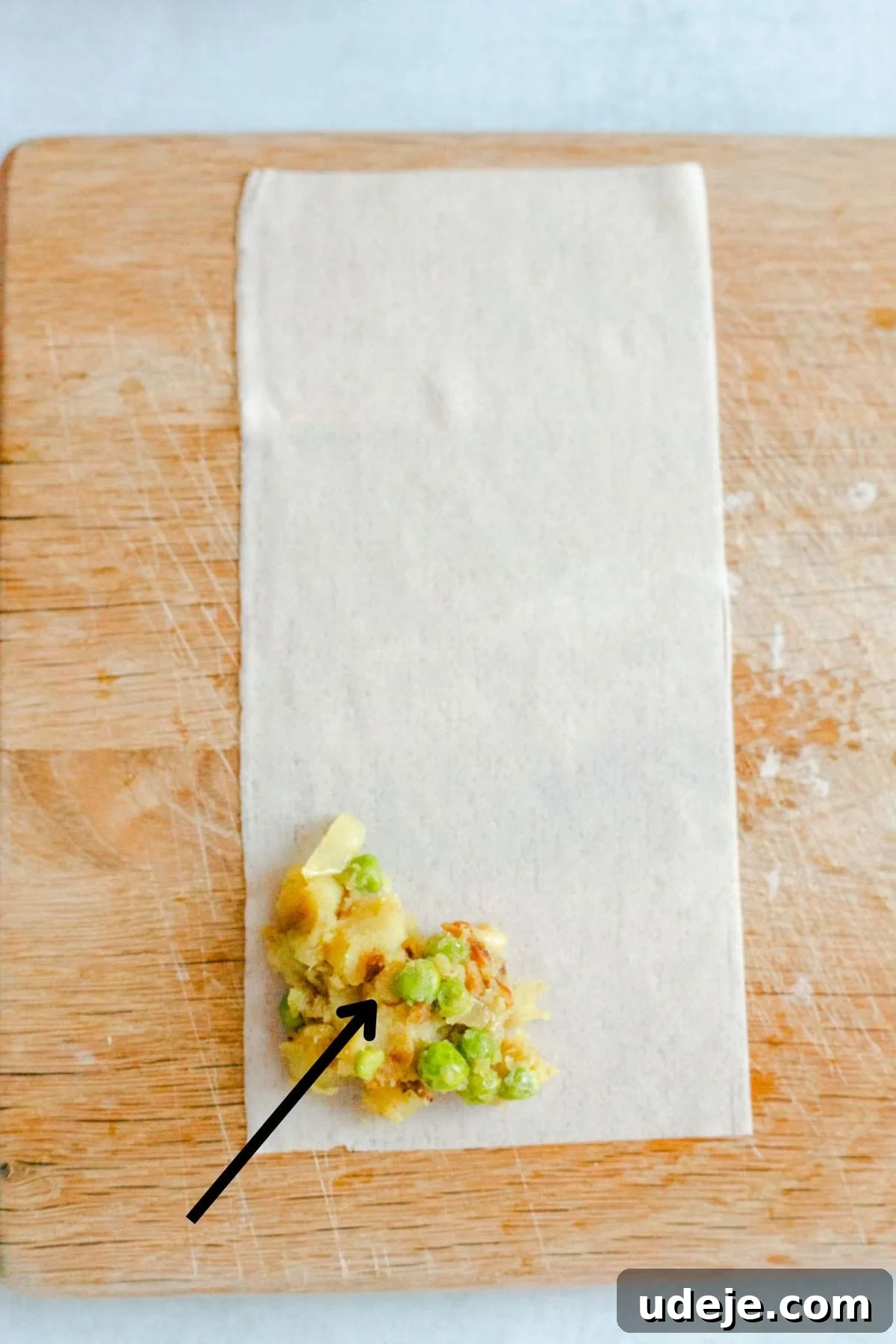 Your Guide to Authentic Homemade Sambousek 18 a square spring roll wrapper on a wooden board, with a potato and pea filling