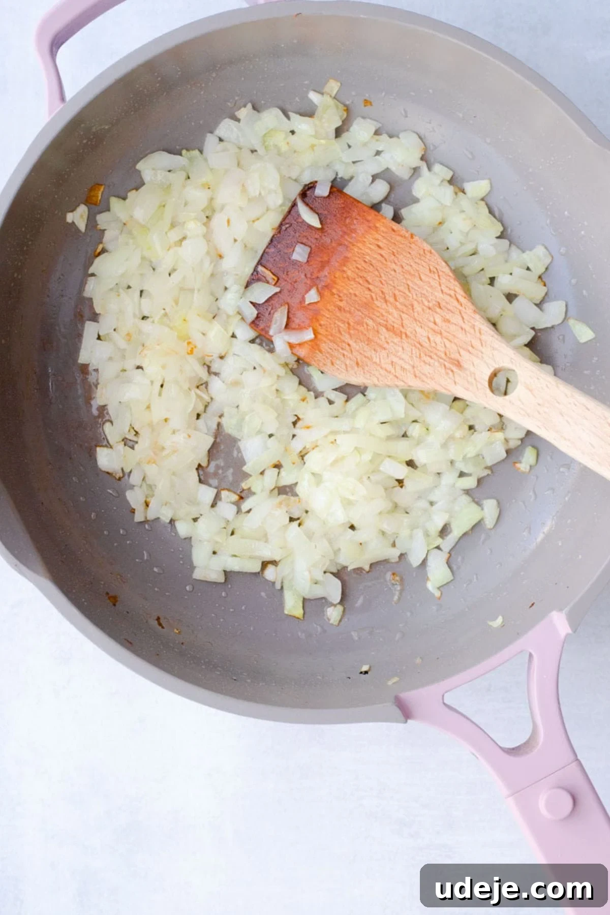 Your Guide to Authentic Homemade Sambousek 5 diced onions being cooked in a pan with a wooden spoon