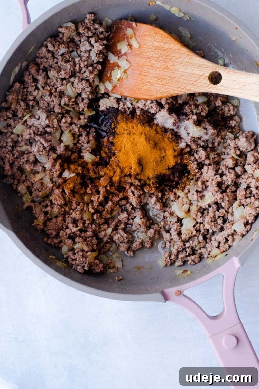 Your Guide to Authentic Homemade Sambousek 6 ground beef with onions and spices being cooked in a pan with a wooden spoon