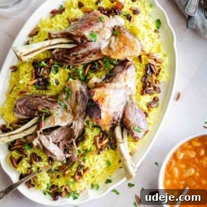 A platter of Quzi-style cooked lamb shanks served over yellow rice with raisins, herbs, and nuts, accompanied by bowls of yogurt, tomato stew, chopped herbs, cutlery, and salt shakers nearby.