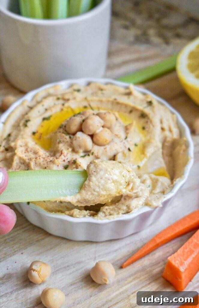 Effortlessly Craft Your Own Hummus 3 A perfectly smooth and creamy bowl of homemade hummus, ready to be garnished and served with fresh vegetables and pita bread.