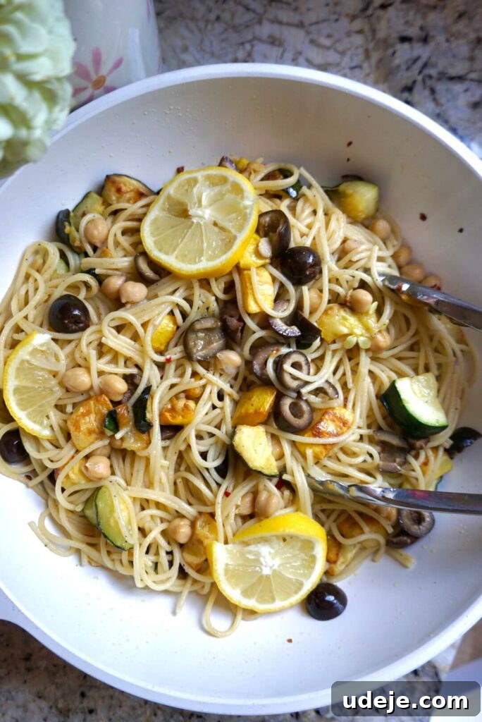 Vibrant Summer Squash Pasta 3 Close-up shot of the finished Vegan Summer Squash Pasta, showing the texture of al dente spaghetti mixed with tender zucchini, yellow squash, chickpeas, and sliced black olives, glistening with olive oil and lemon.