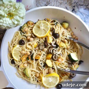 A top-down view of the prepared Summer Squash Pasta, featuring al dente pasta mixed with vibrant yellow and green squash, chickpeas, and black olives, ready to be served.