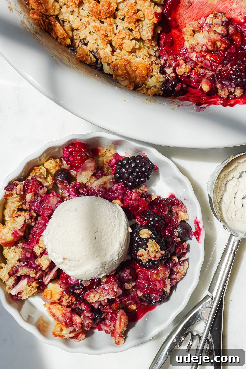 Wholesome Berry Crumble 5 Overhead shot of a bowl of healthy berry crisp topped with a generous scoop of vegan vanilla ice cream.
