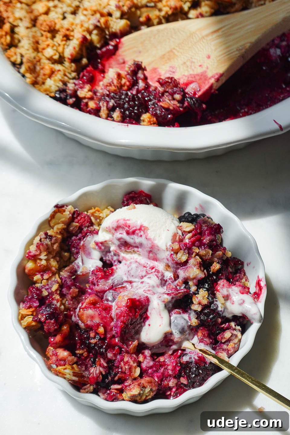 Wholesome Berry Crumble 6 Healthy berry crisp in a bowl with swirls of melting vegan vanilla ice cream, ready to be enjoyed.