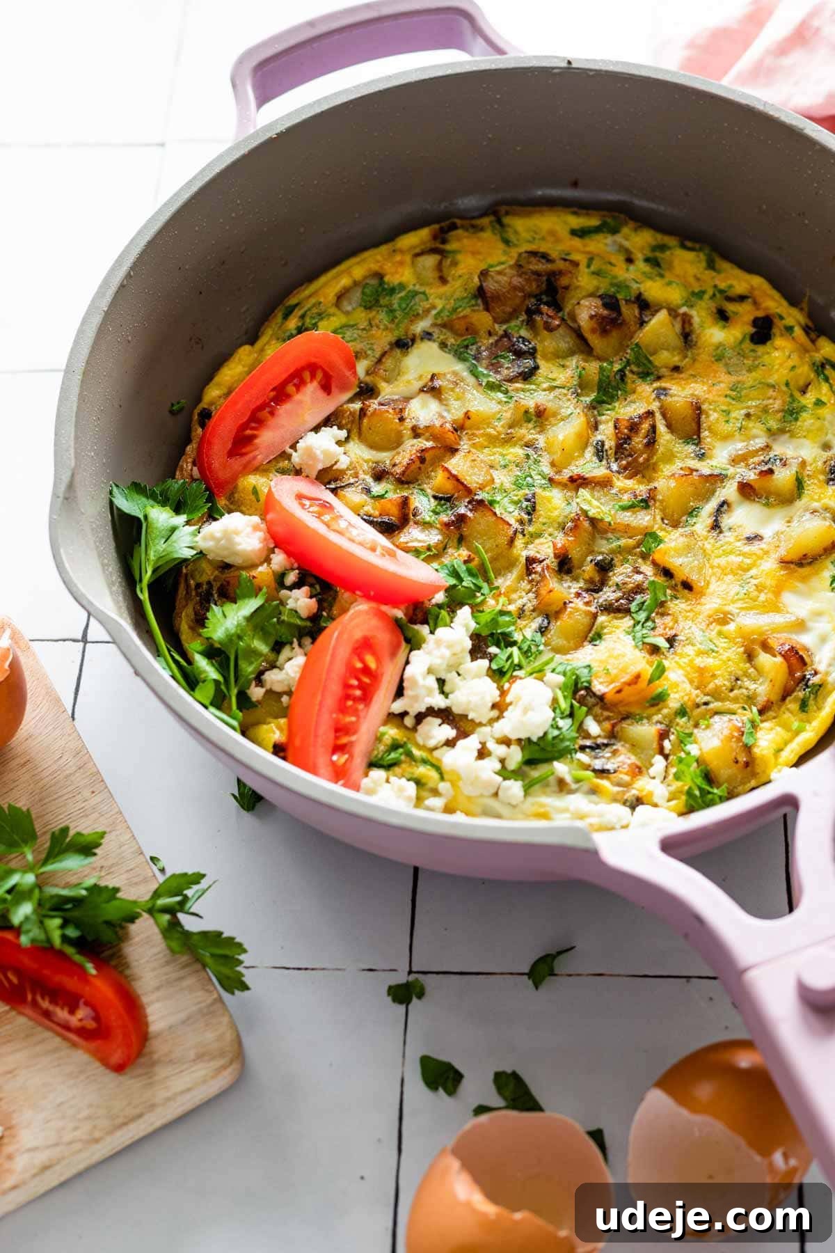 Lazy Sunday Potato Omelette 2 A loaded potato and egg frittata, beautifully presented in a skillet, garnished with fresh sliced tomatoes and crumbled feta cheese, ready to be served.