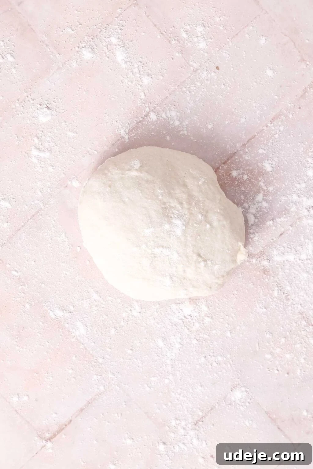 Lahm Bi Ajeen Savory Middle Eastern Flatbread 11 ball of dough on a floured light pink tiled background