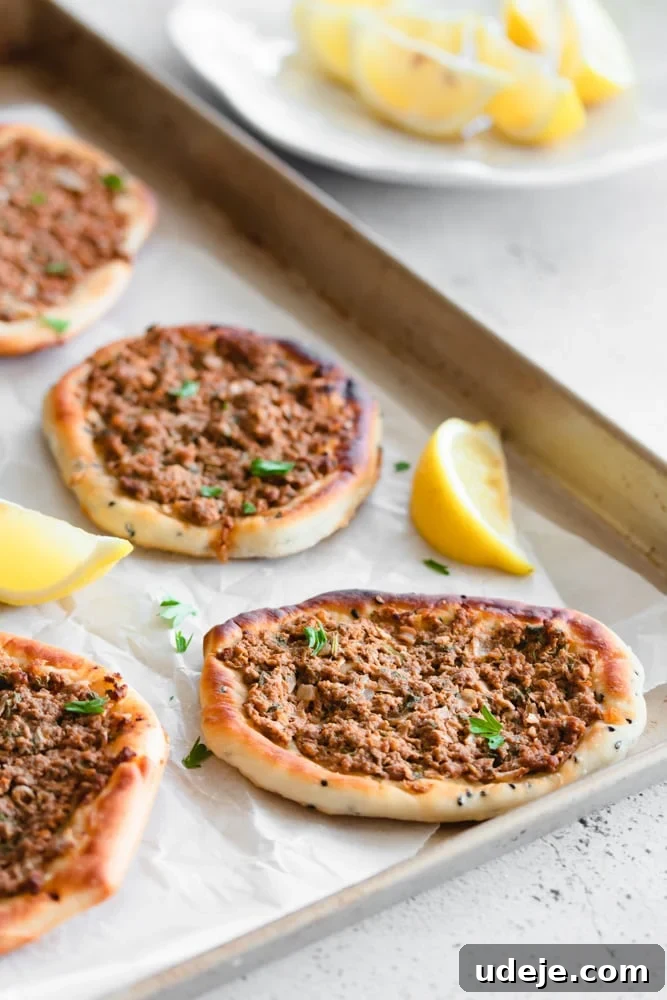 Lahm Bi Ajeen Savory Middle Eastern Flatbread 17 Lahm Bi Ajeen or Sfiha on wax paper with lemon wedges
