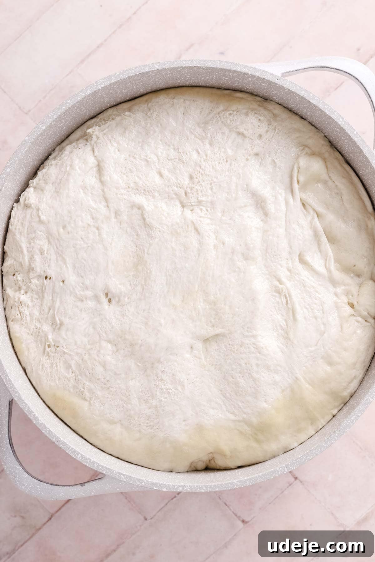 Lahm Bi Ajeen Savory Middle Eastern Flatbread 6 risen dough in a light coloured pot on a light pink tiled background