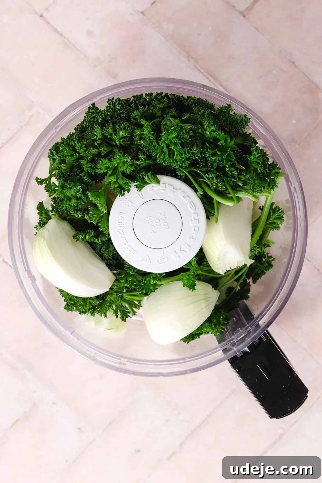 Lahm Bi Ajeen Savory Middle Eastern Flatbread 7 Onions and parsley in a food processor on a light pink tiled backdrop