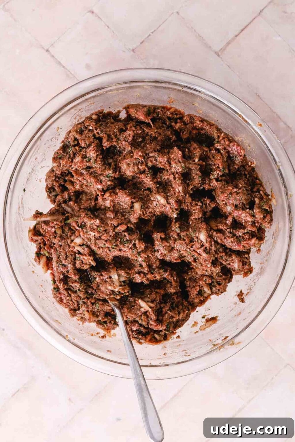 Lahm Bi Ajeen Savory Middle Eastern Flatbread 10 meat mixture in a glass bowl on a light pink tiled background