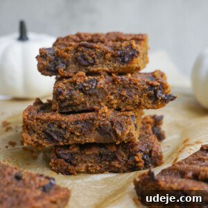 Vegan Gluten Free Pumpkin Peanut Butter Blondies 3 A top-down shot of freshly baked Pumpkin Peanut Butter Blondies in a baking dish, cut into squares, with a piece removed.