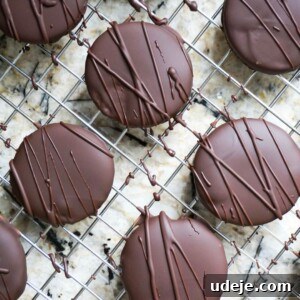 A stack of perfectly coated homemade Thin Mints, showcasing their dark chocolate shell and hint of minty green inside.
