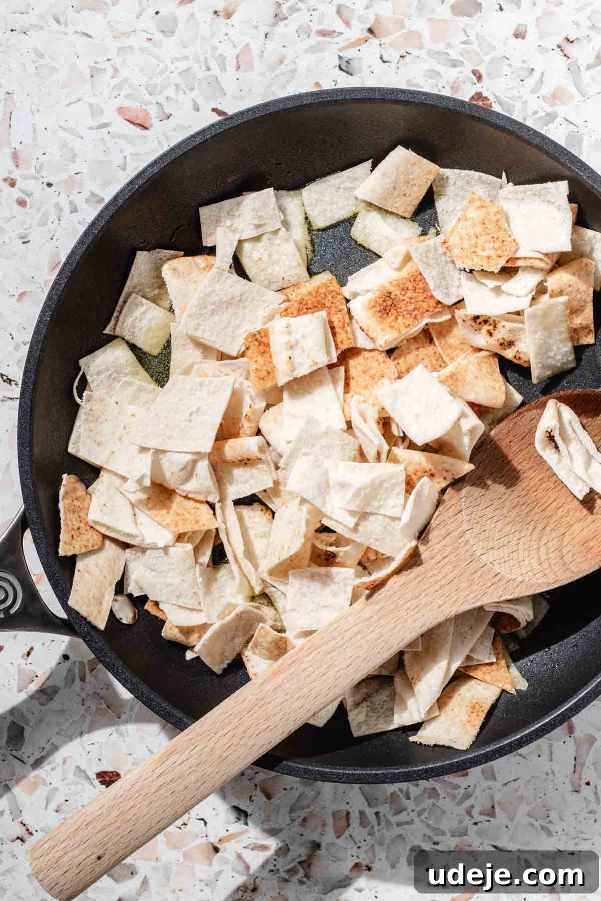 Signature Restaurant Fattoush 4 pita bread cut up in small one inch squares placed in a medium black skillet with a wooden spoon