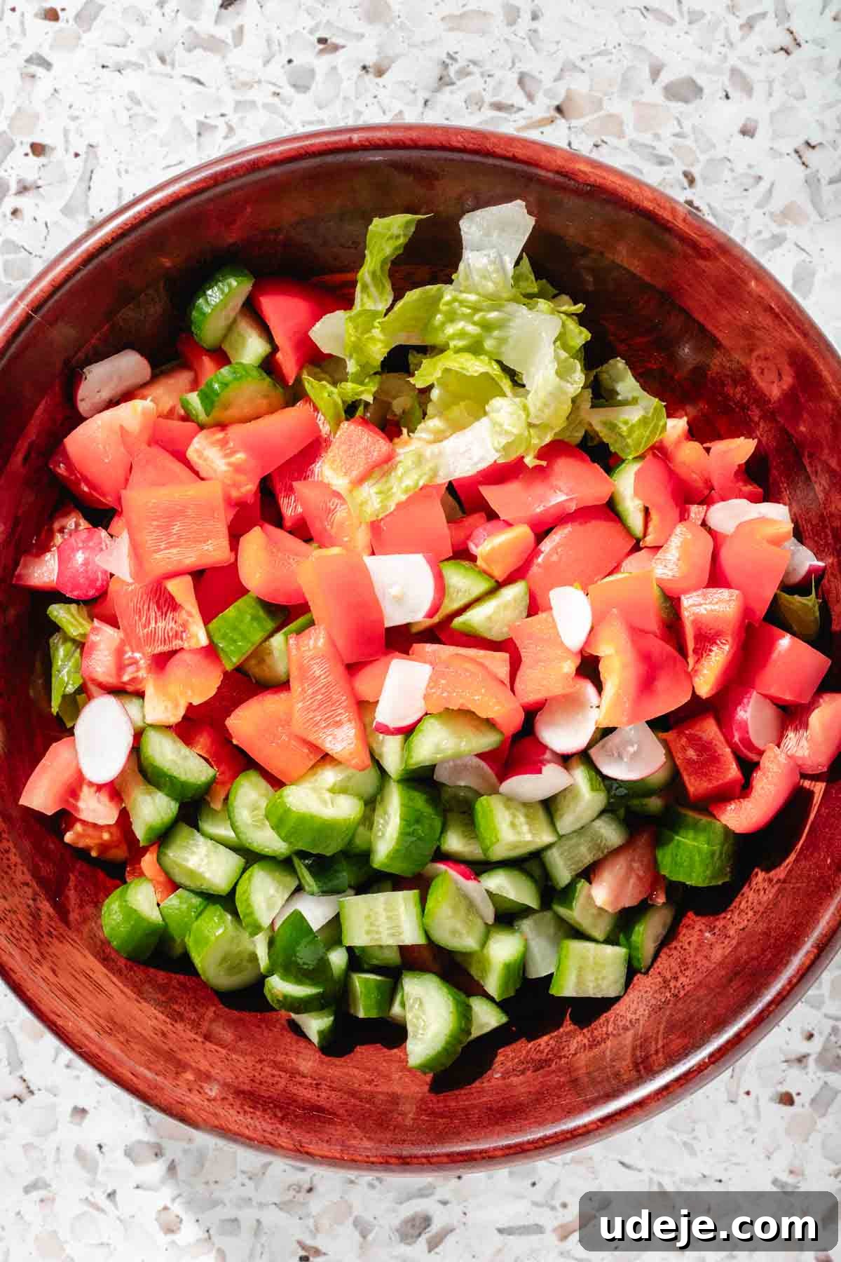 Signature Restaurant Fattoush 6 A fattoush salad in a wooden salad bowl, which includes chopped lettuce, cucumber, red pepper, radish and tomatoes