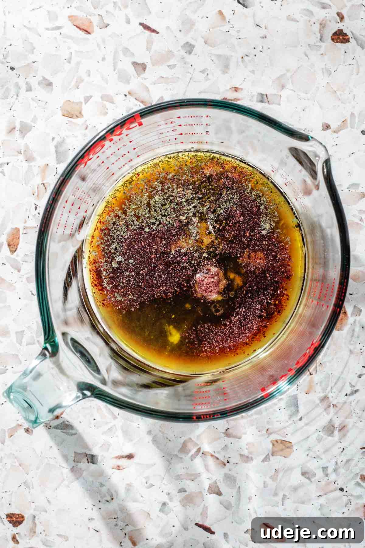 Signature Restaurant Fattoush 7 Fattoush salad dressing in a glass measuring cup, which includes olive oil, lemon juice, pomegranate molasses, mint, sumac and garlic